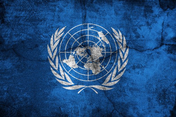 The UN logo on a cracked blue surface, representing global governance and challenges in cybercrime policies.