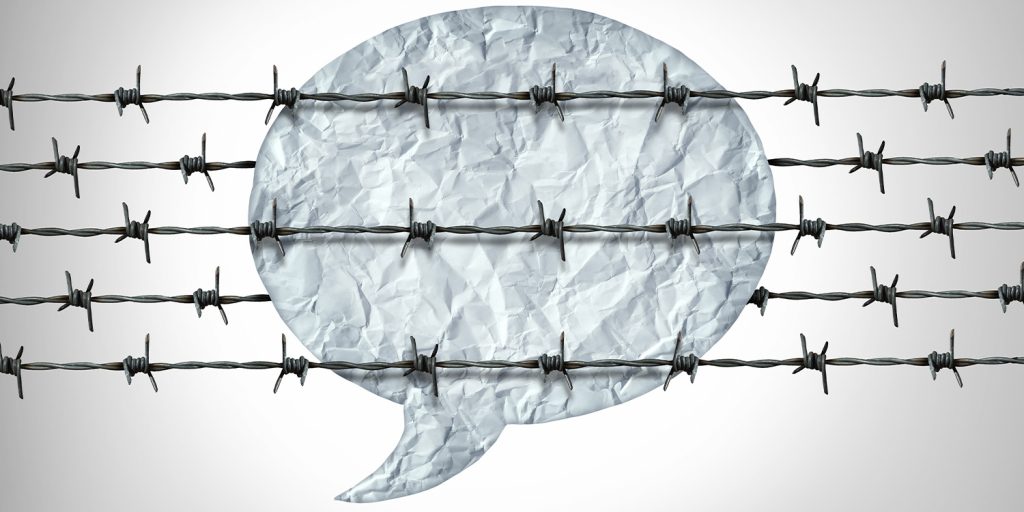 Speech bubble wrapped in barbed wire, symbolizing restrictions on free speech and online expression.